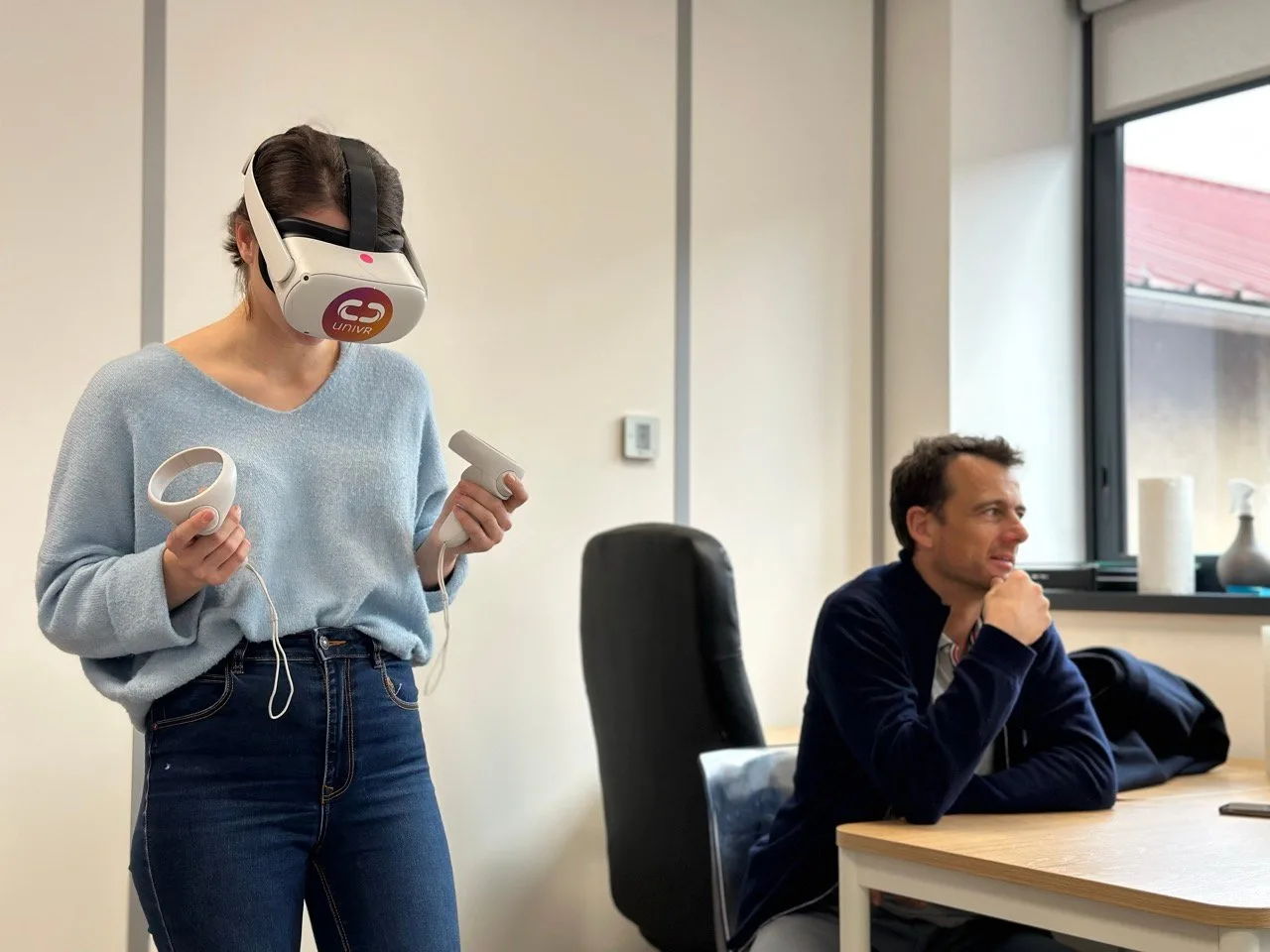 Une interne casquée s'entraîne au geste en réalité virtuelle, un chirurgien assis à ses côtés