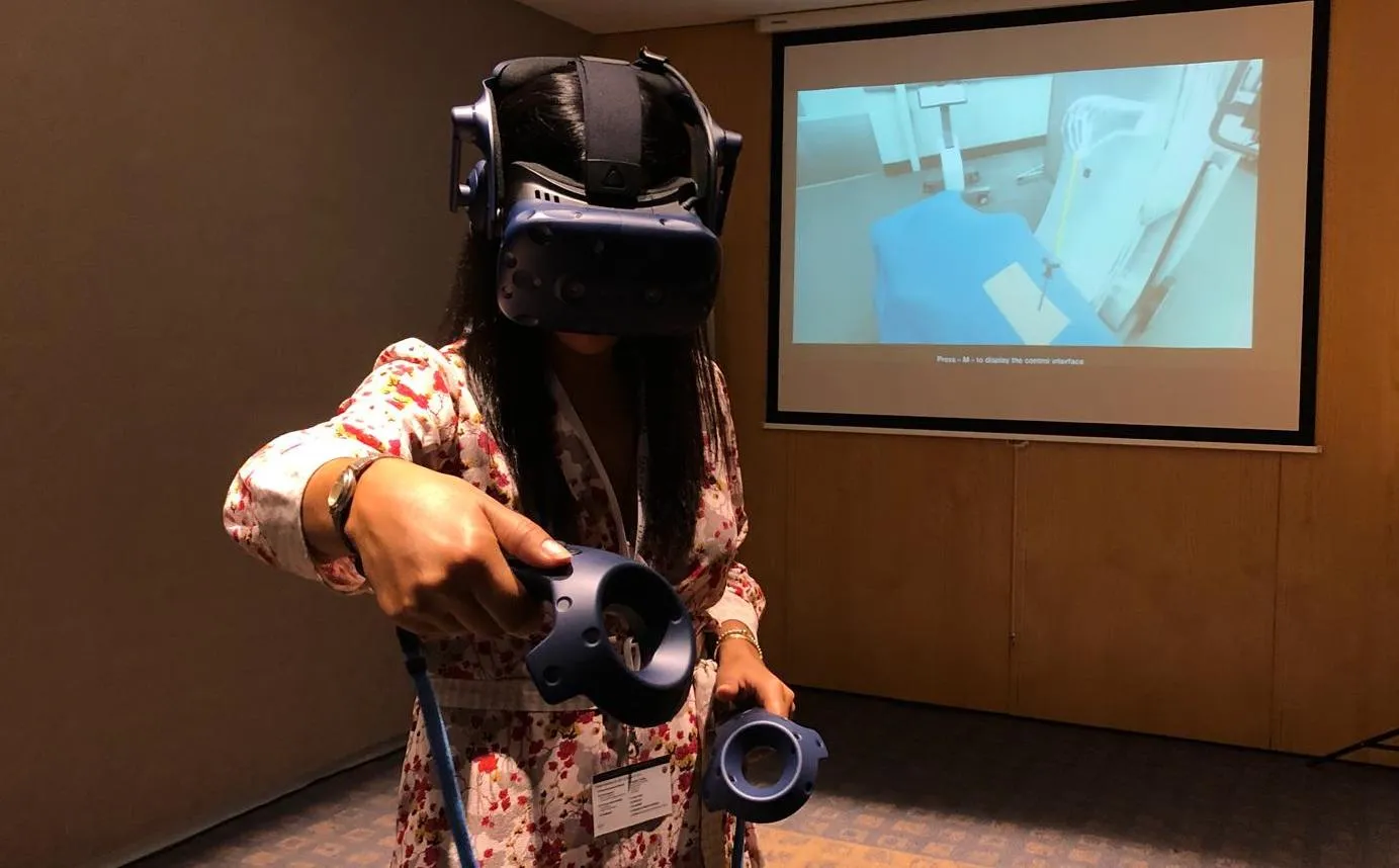 Une chirurgienne casquée, manettes en main, pratique la procédure en réalité virtuelle devant l'écran qui retransmet sa vue