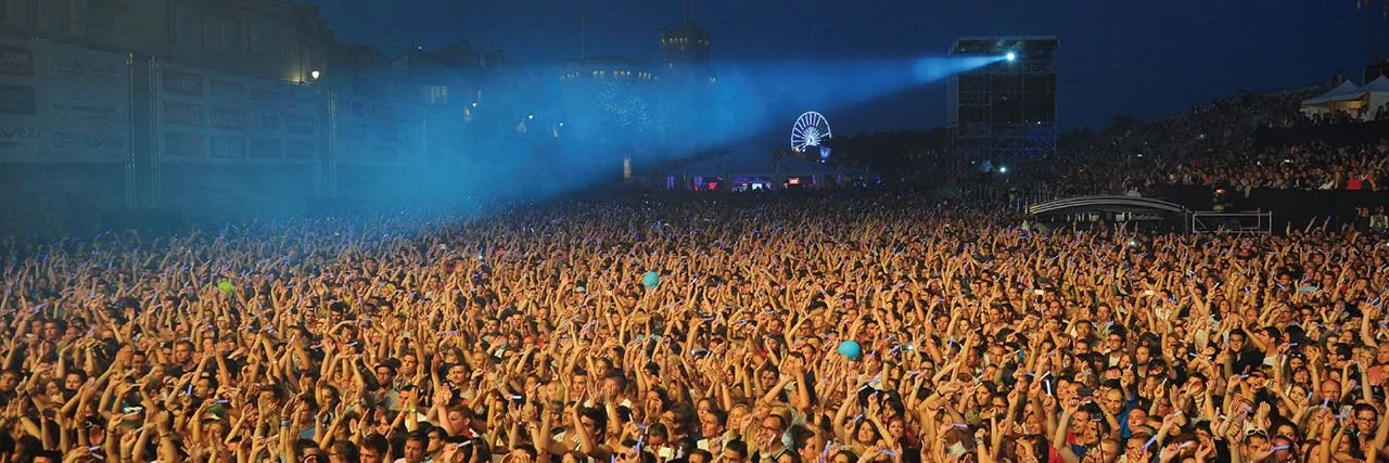 Foule d'un festival de musique vue depuis la scène, éclairée en bleu.