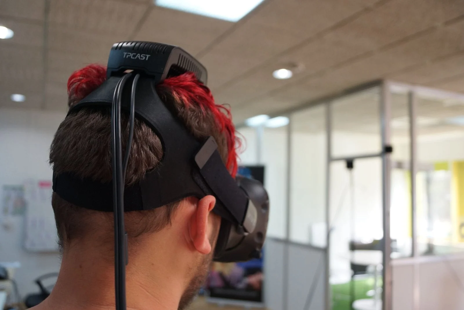 Vue de dos : le module TPCast fixé sur la sangle du casque, relié par un câble.