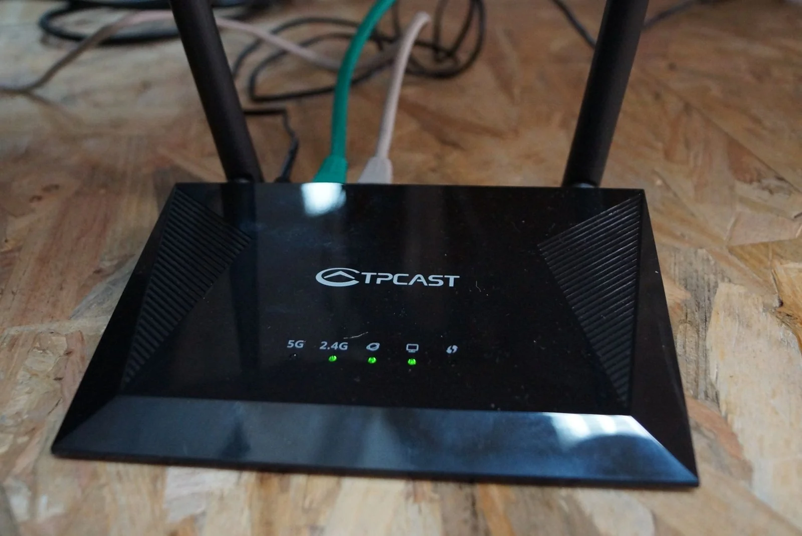 Routeur TPCast posé au sol, antennes déployées et voyants allumés.