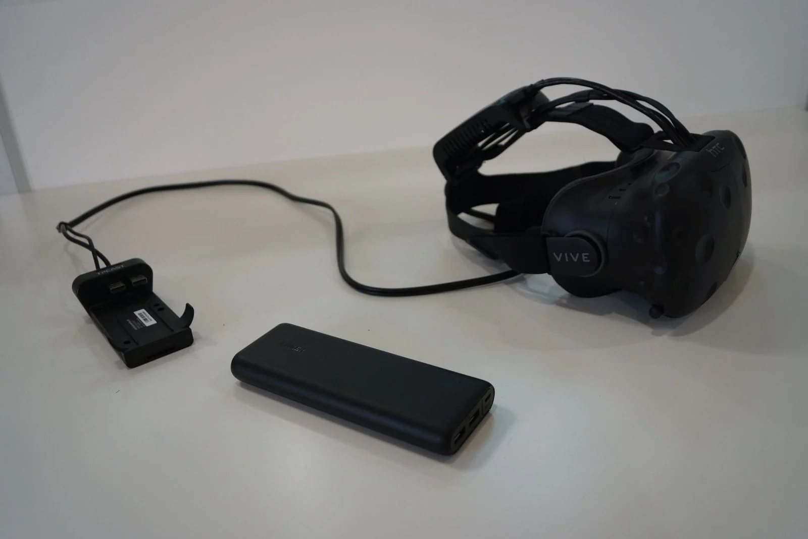 Casque HTC Vive posé à côté de la batterie et de l'adaptateur TPCast.